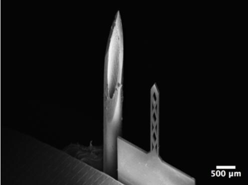 開孔鈦基微針（200um寬，50um厚，1500um長）和26G皮下注射針（外徑464um）對比的掃描電子顯微鏡照片